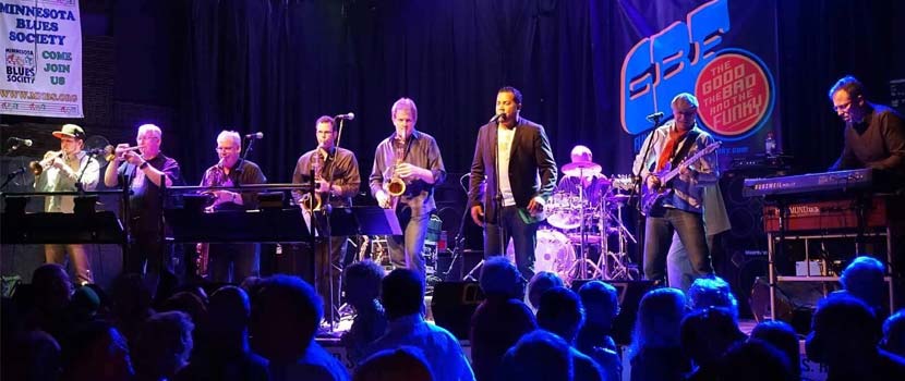 A band, featuring saxophones, trumpets and a vocalist, plays.