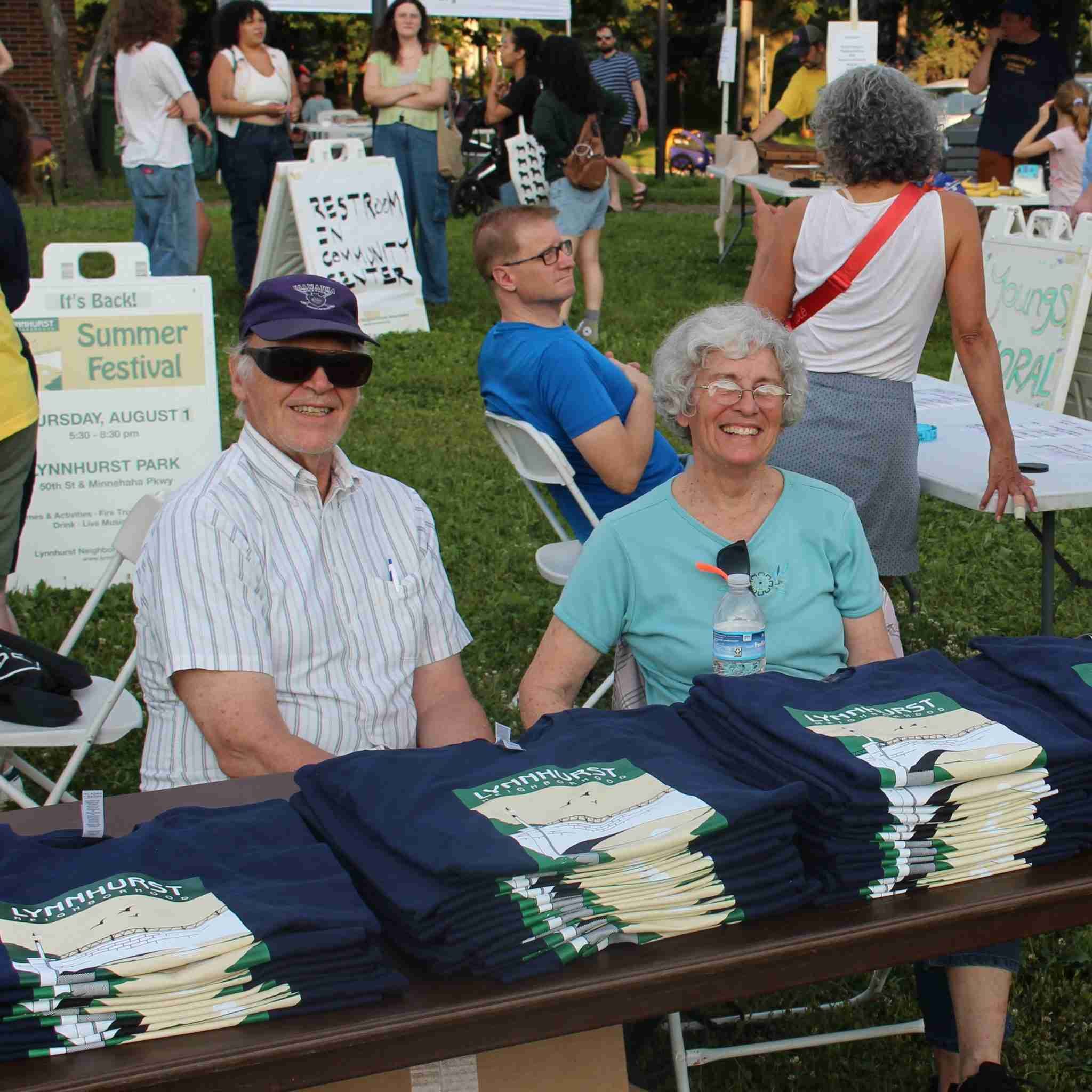 Two people selling t-shirts at Lynnhurst Summer Festival