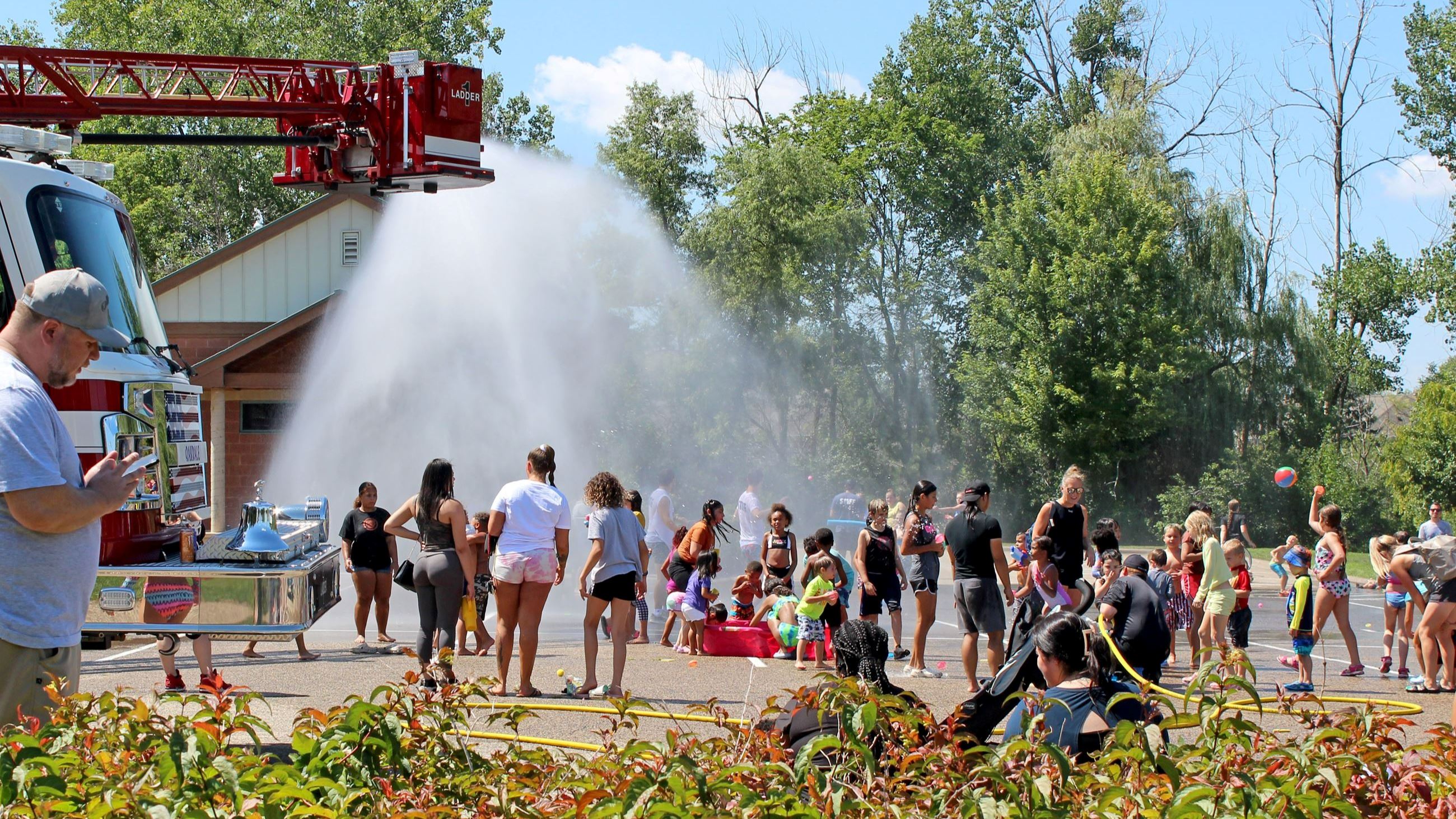 Families under fire truck spray